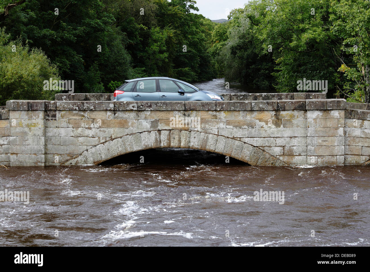 Lochlip Road, Lochwinnoch, Renfrewshire, Schottland, Großbritannien, Sonntag, 15. September 2013. Ein Auto überquert die alte Steinbrücke, nachdem heftiger Regen hohe Flussniveaus und schnell fließendes Wasser auf dem Fluss Calder verursachte Stockfoto