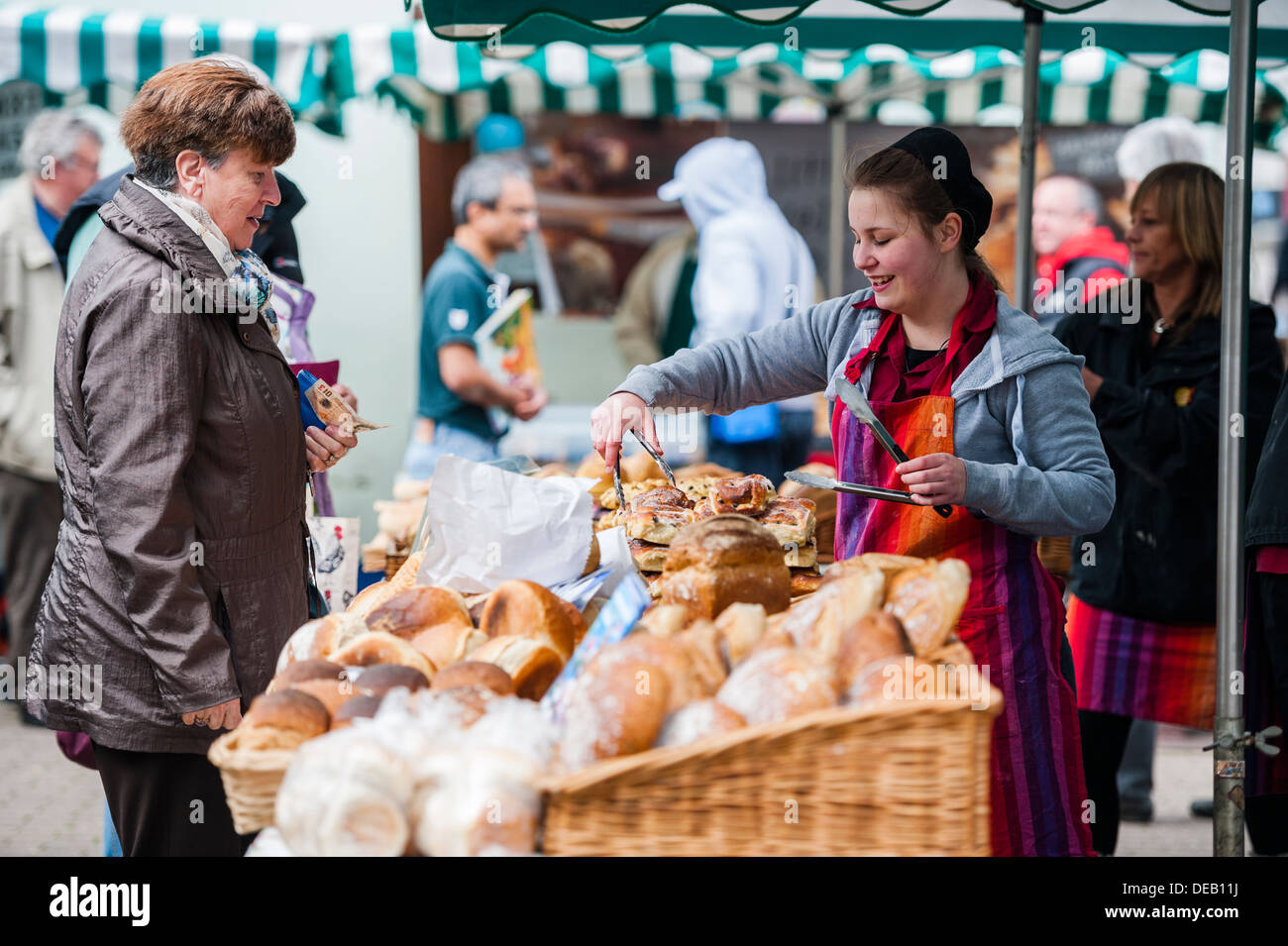 Eine junge Frau verkaufen frisches Brot auf Bauernmarkt Haverfordwest, Pembrokeshire. Wales UK Stockfoto