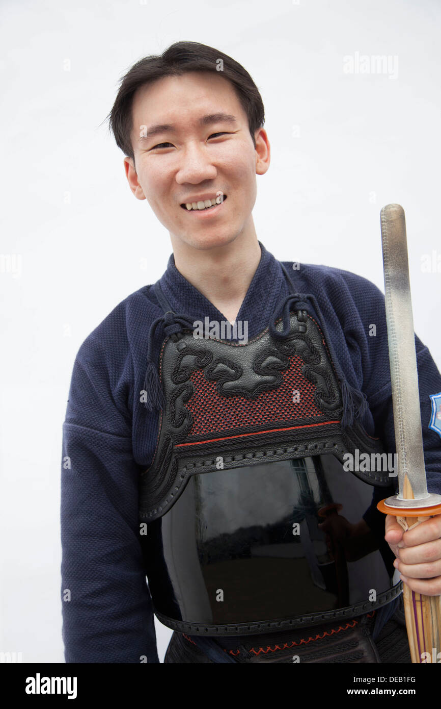 Porträt der jungen lächelnd Mann in der traditionellen japanischen Kleidung mit einem Schwert, Studio gedreht Stockfoto