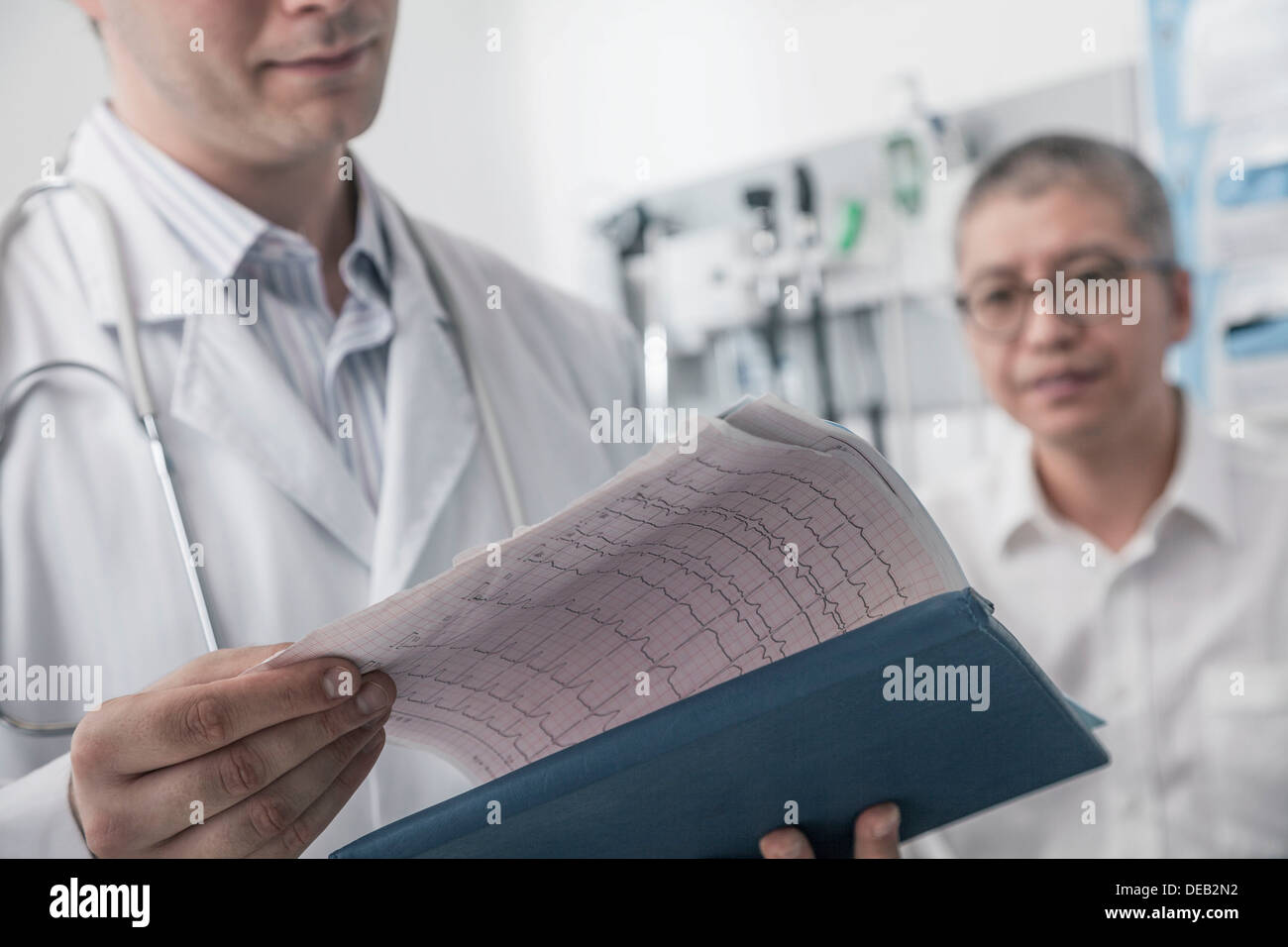 Arzt überprüft medizinische Diagramm mit Patienten im Hintergrund Stockfoto