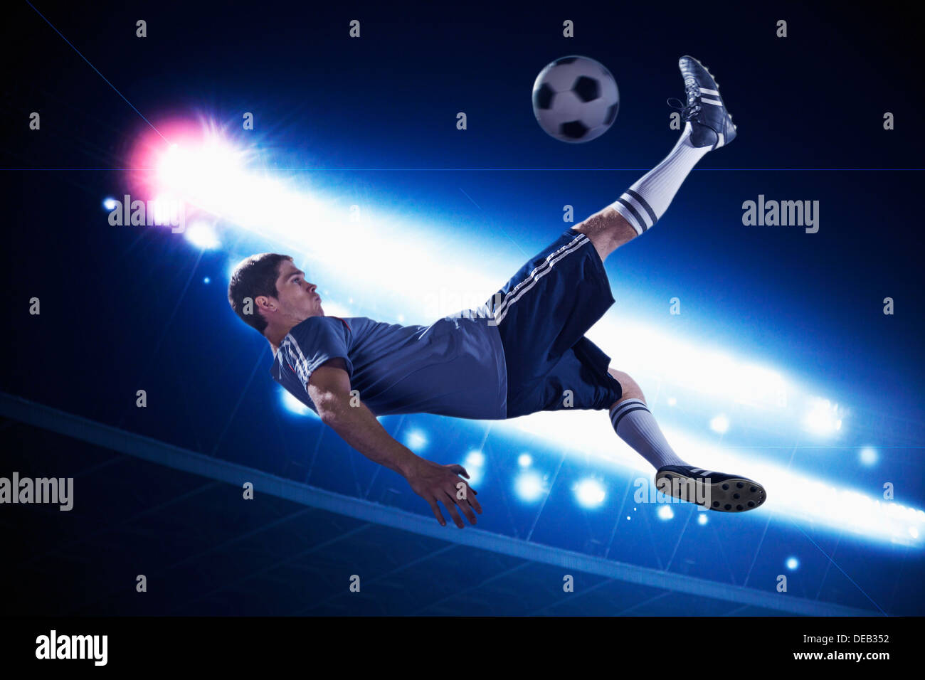 Fußball-Spieler in der Luft treten die Fußball, Stadion Lichter in der Nacht im Hintergrund Stockfoto