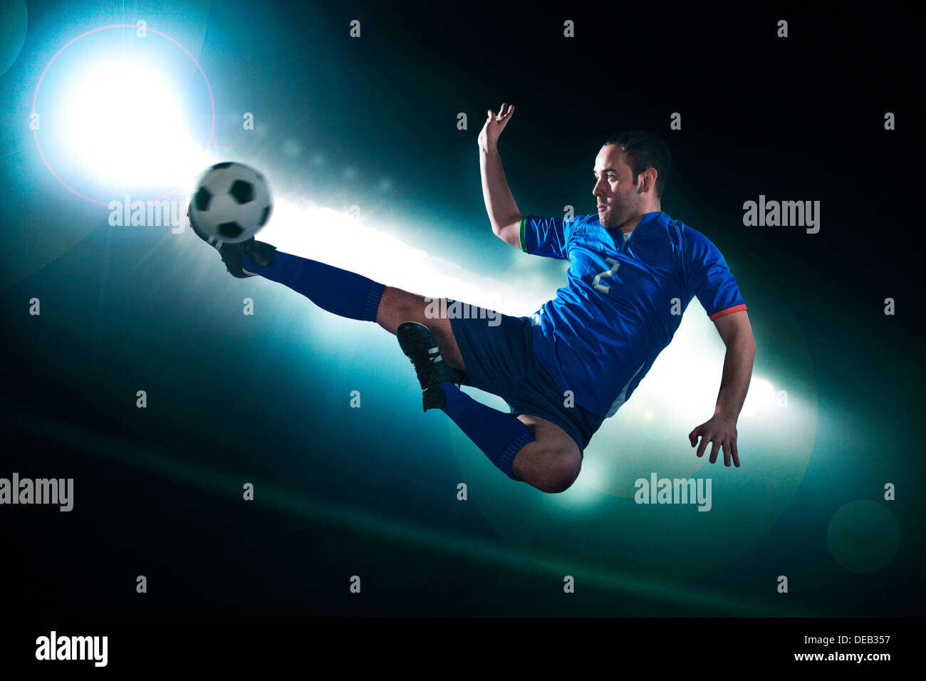 Fußball-Spieler in der Luft treten die Fußball, Stadion Lichter in der Nacht im Hintergrund Stockfoto