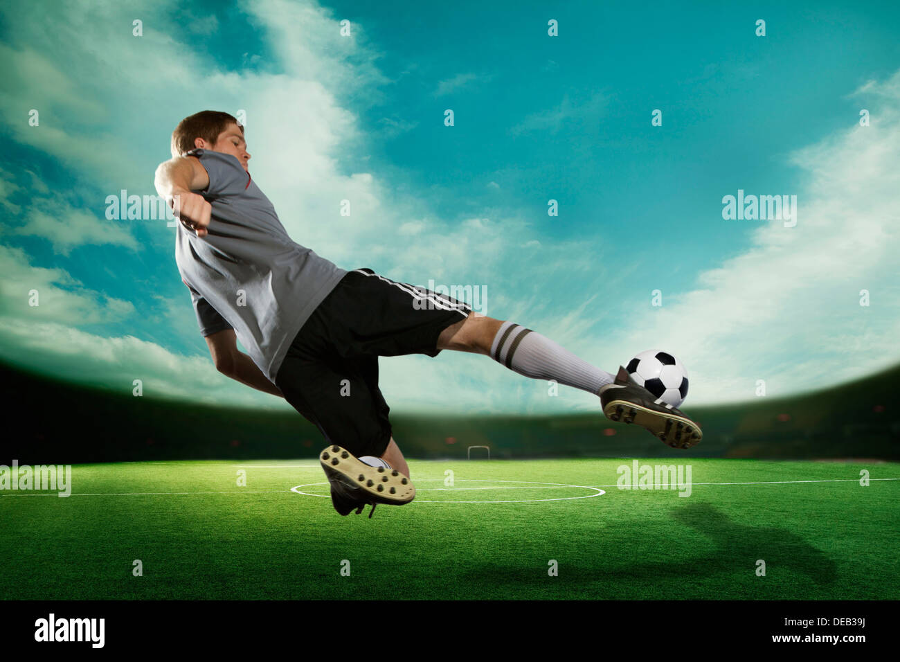 Fußball-Spieler, die den Fußball-Ball in der Luft, im Stadion mit dem Himmel Stockfoto