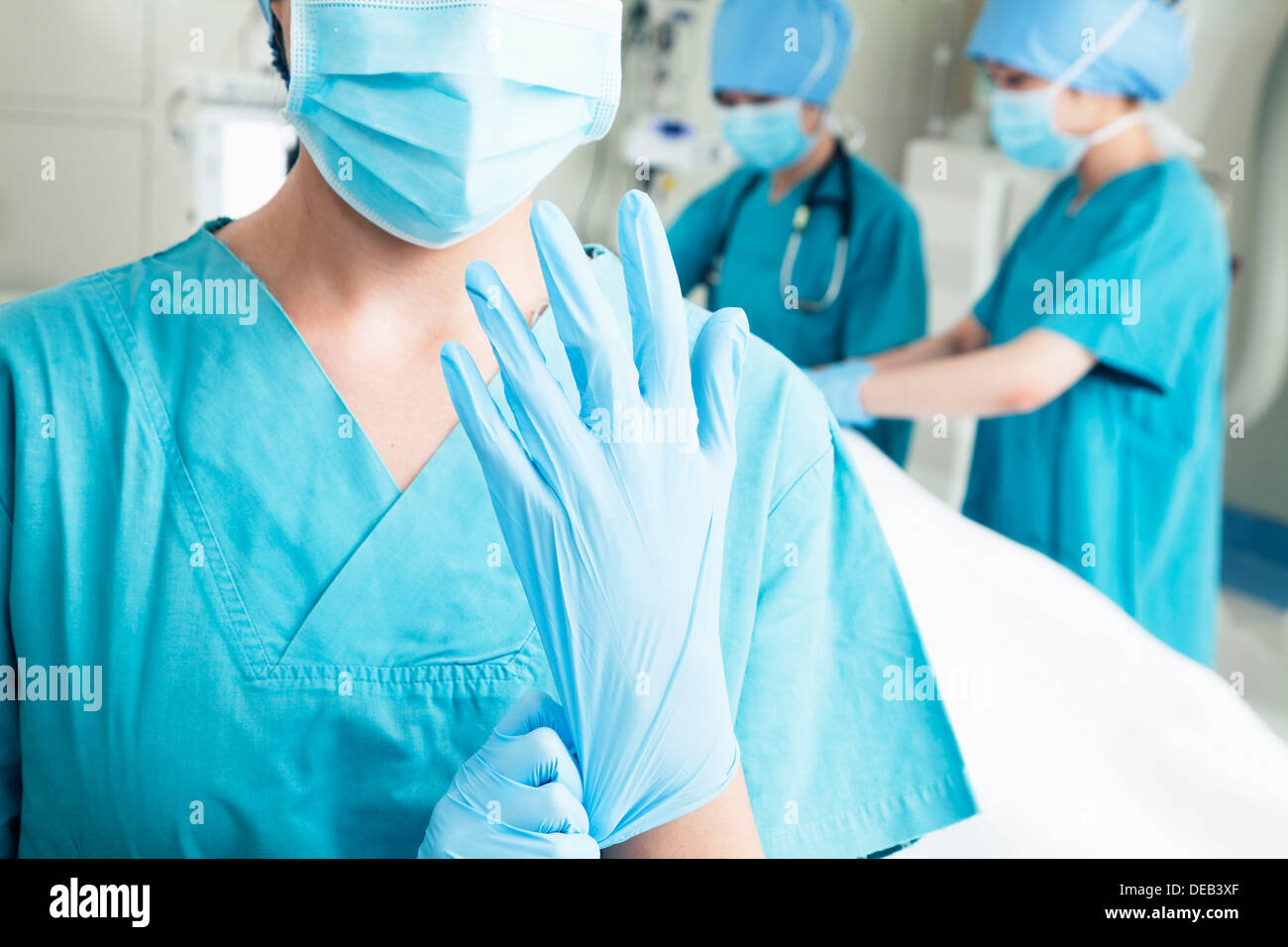 Weibliche Chirurg anziehen Handschuhe im OP-Saal, Mittelteil Stockfoto