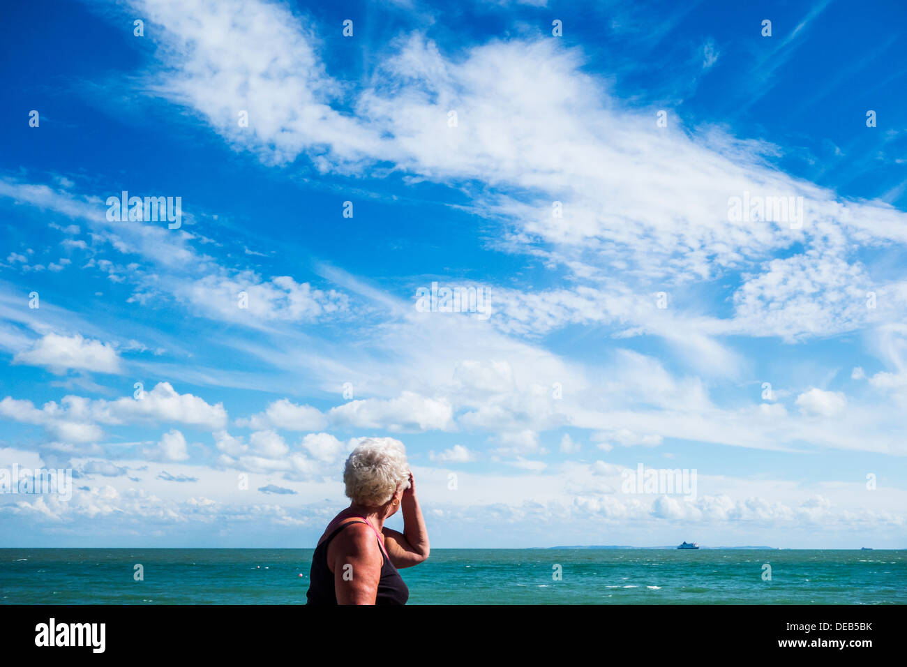 Ältere Rentner Frau zu Fuß am Meer Skyscape Stockfoto