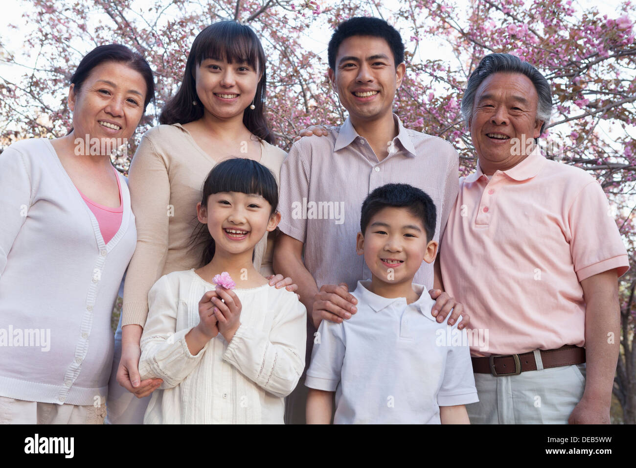 Porträt eines Lächeln mehr-Generationen-Familie unter den Kirschbäumen und genießen den Park im Frühling Stockfoto