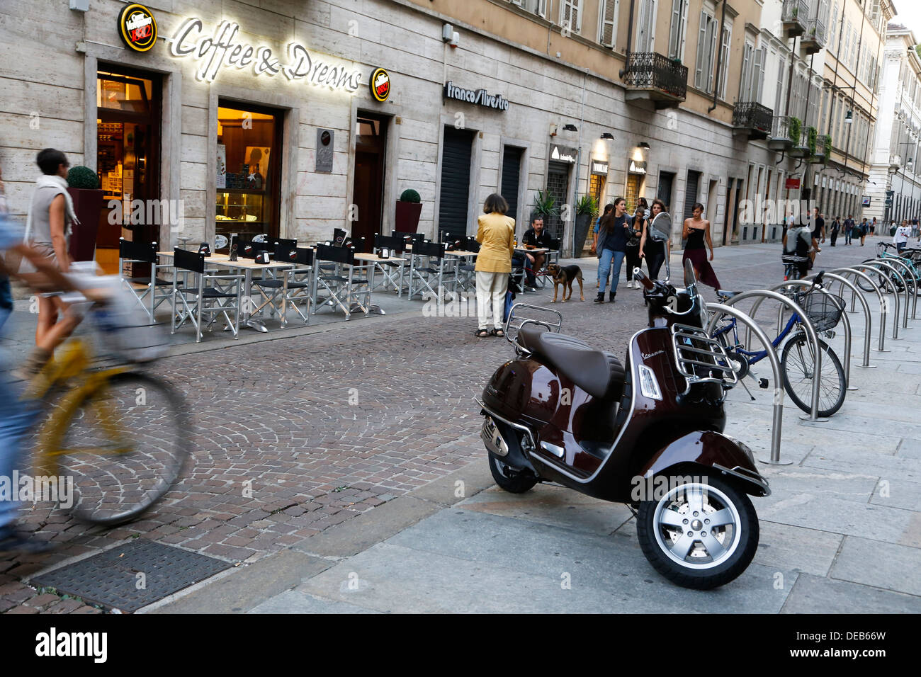 Via di Torino mit Fußgänger und Fahrräder, im Vordergrund ein Vespa Roller Stockfoto