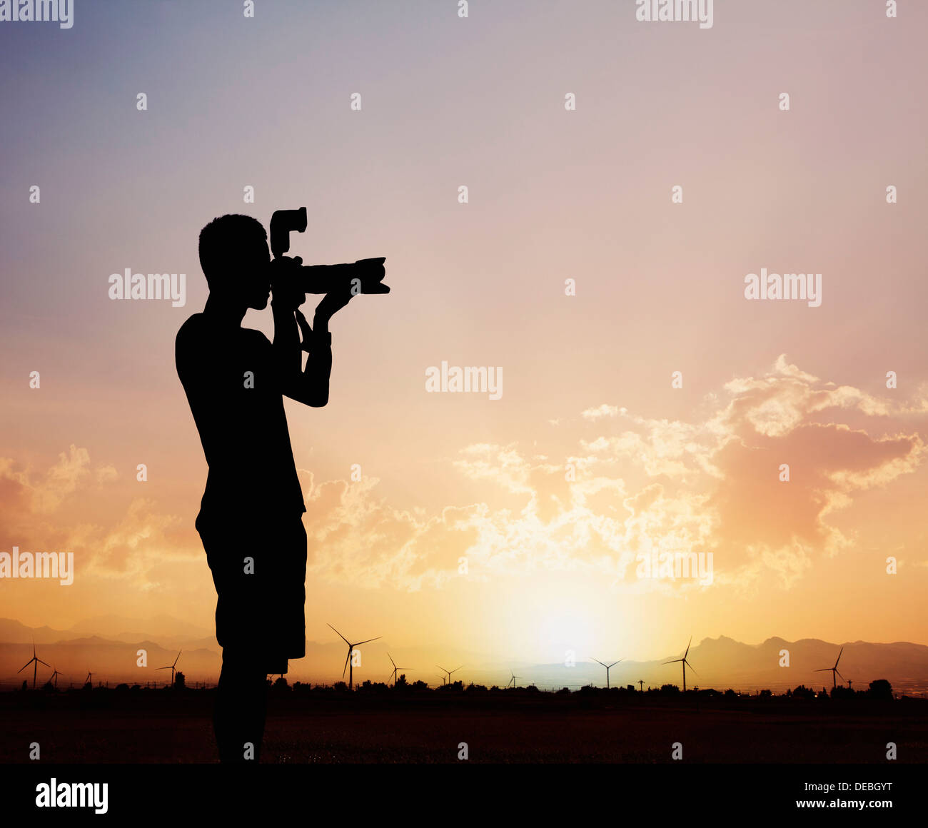 Silhouette des Menschen mit seiner Kamera bei Sonnenuntergang mit einem dramatischen Himmel fotografieren Stockfoto