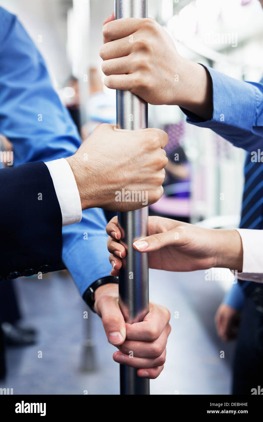 Nahaufnahme von vier Geschäftsleuten Hände halten die Pole in der u-Bahn Stockfoto