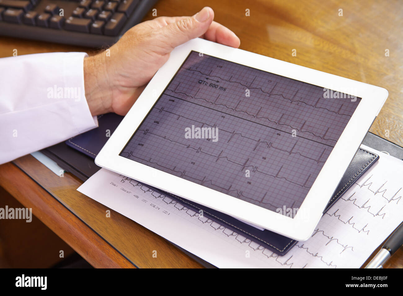 Arzt, Blick auf ECG auf einem Tabletcomputer in seinem Büro Stockfoto