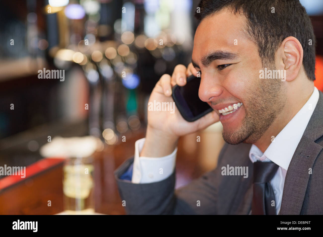 Fröhliche gut aussehend Geschäftsmann auf dem Handy einen Drink Stockfoto