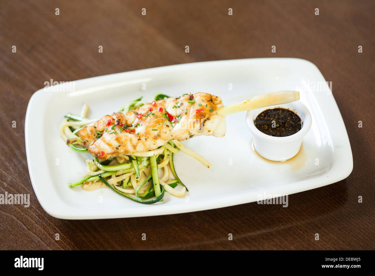 Asiatisch inspirierte Fischgericht mit Nudeln und Julienne-Gemüse Stockfoto