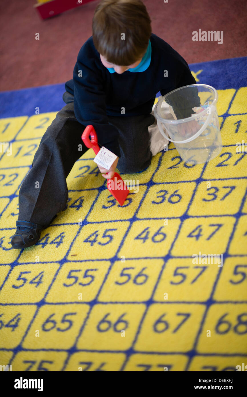 Junge Schüler spielen auf einem nummerierten Teppich in einer Grundschule, Wales UK Stockfoto
