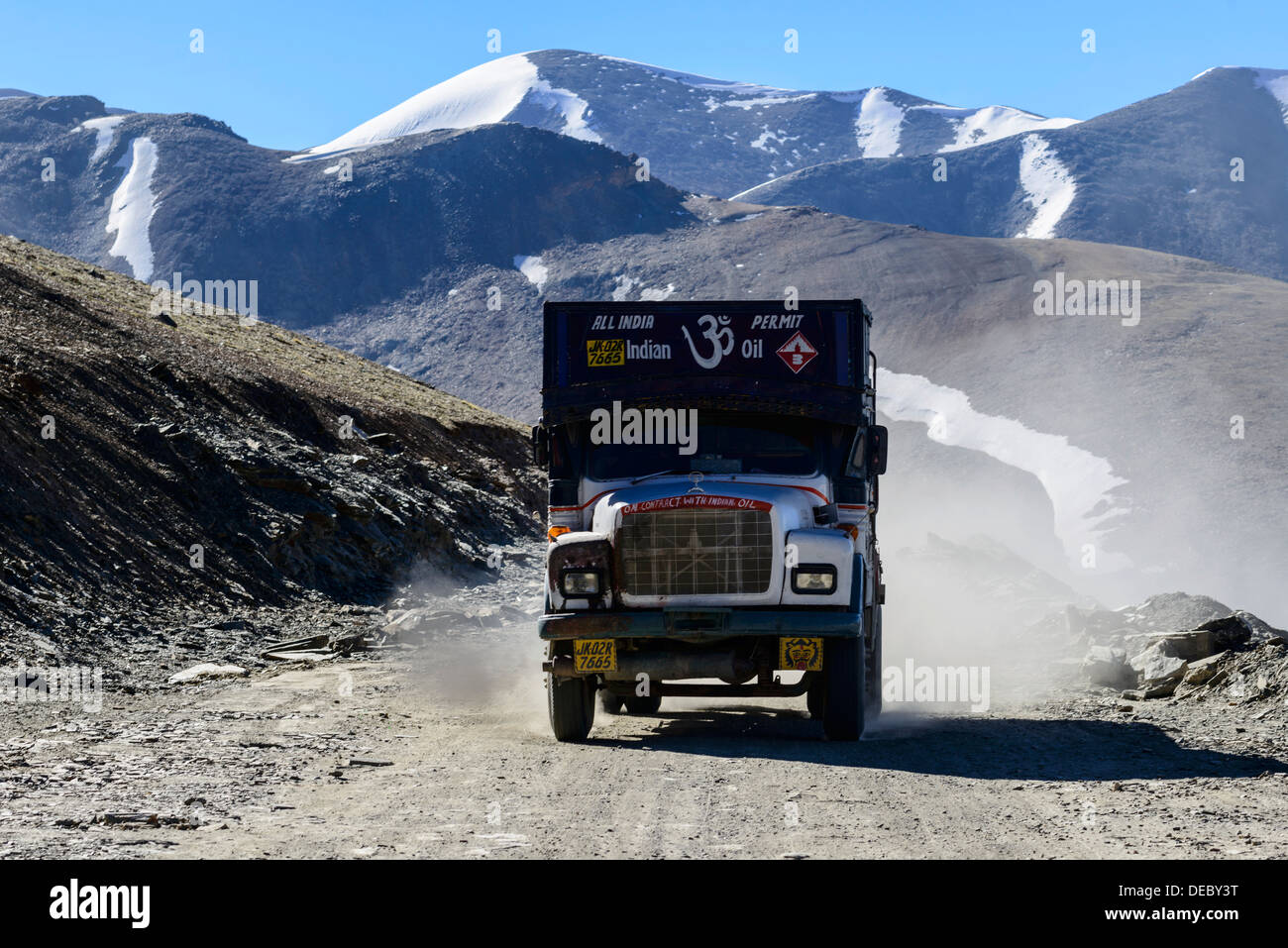 Ein LKW-fahren auf der staubigen kurvenreichen Straße im Vorfeld Taglang La, 5,325 m, dem höchsten Pass auf der Manali-Leh-Highway, Schnee Stockfoto