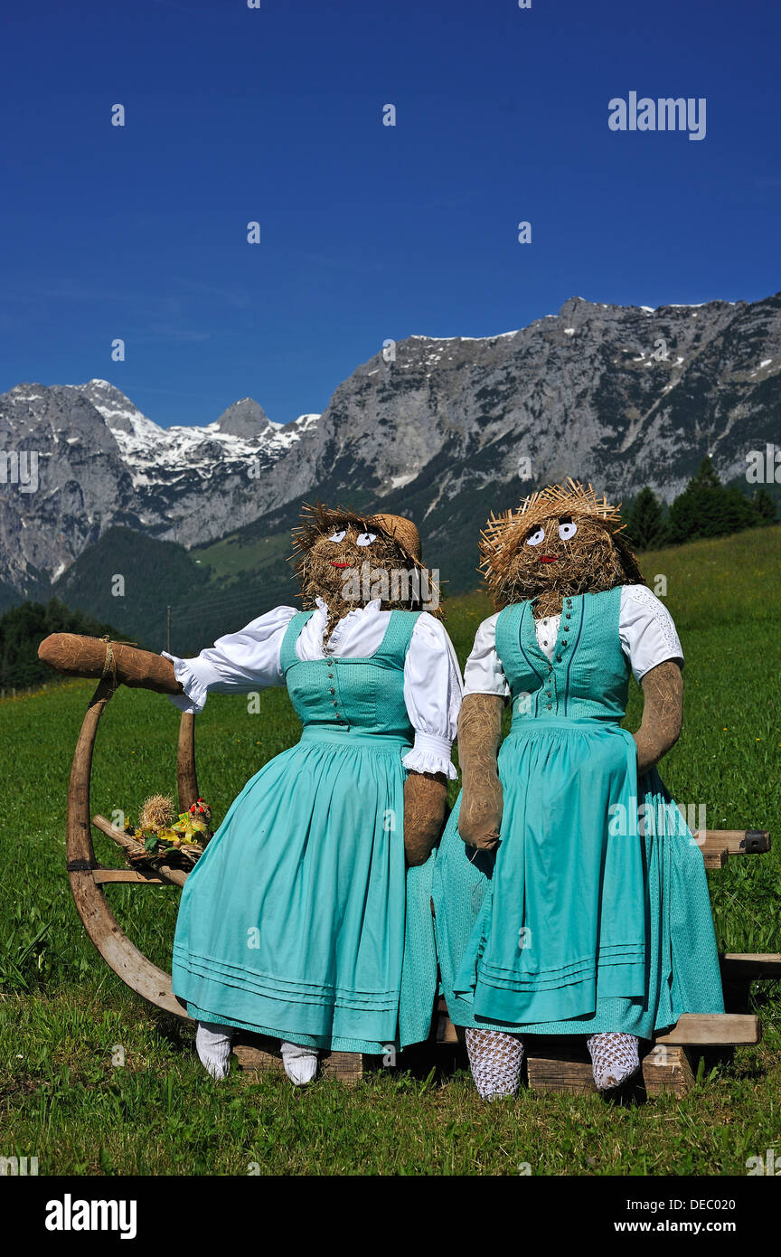 Zwei Stroh Puppen oder Figuren im Dirndl Kleider sitzen auf einem Schlitten  mit lange Horn-förmigen Läufer auf einer Wiese Stockfotografie - Alamy