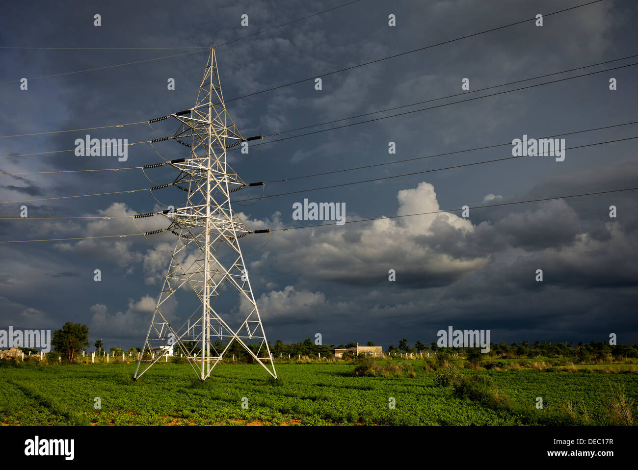 Strommasten und Kabel in der indischen Landschaft gegen einen dunklen Gewitterhimmel. Andhra Pradesh, Indien Stockfoto