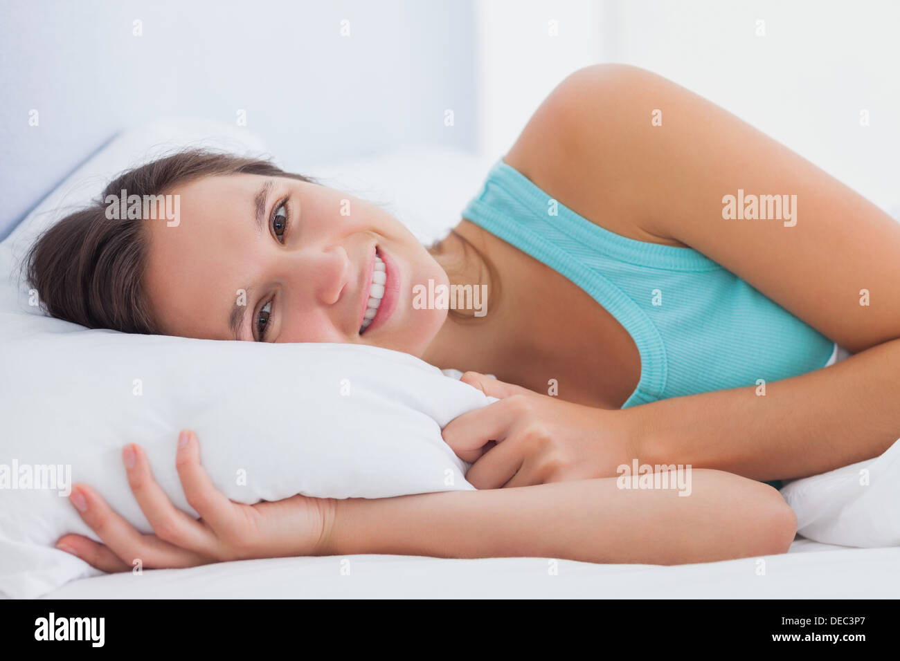 Frau im Bett mit geöffneten Augen und Lächeln Stockfoto