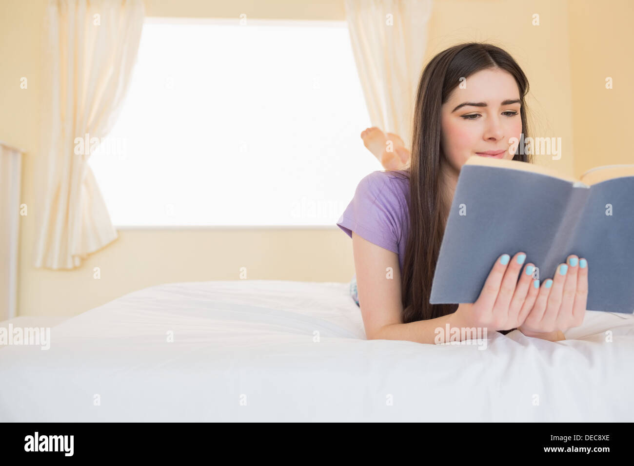 Inhalt Mädchen liegend auf einem Bett, ein Buch zu lesen Stockfoto