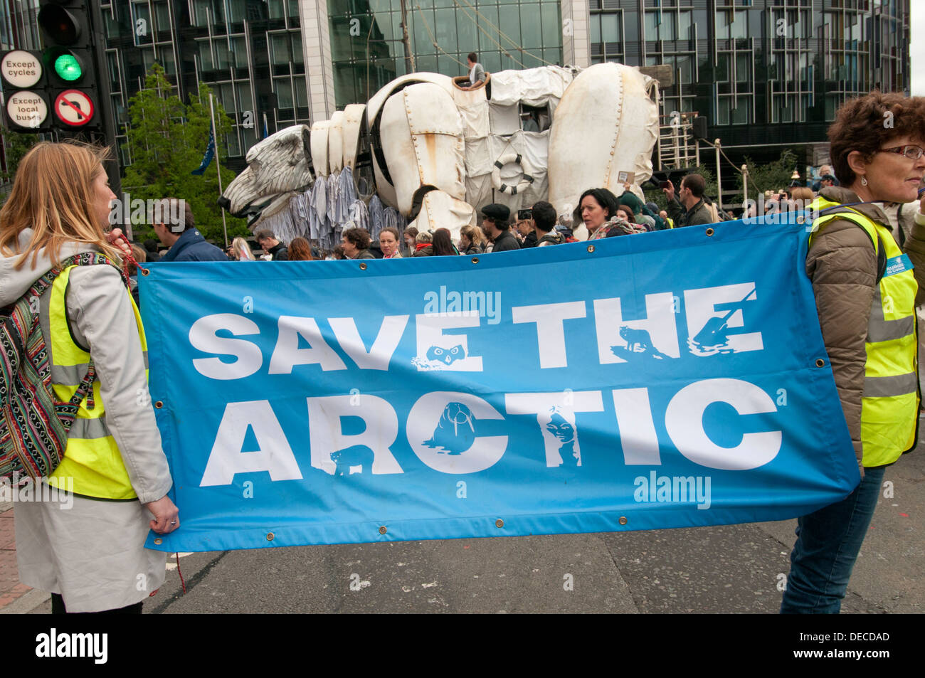 Zwei Stewards halten einen Banner sagen "Speichern the Arctic" vor Aurora, die zweistelligen-Doppeldecker-Bus-Größe Eisbär-Marionette Stockfoto
