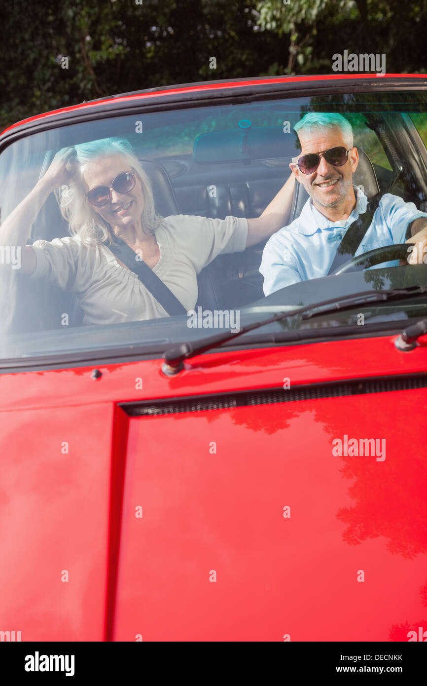 Älteres Paar im roten Cabrio in die Kamera Lächeln Stockfoto