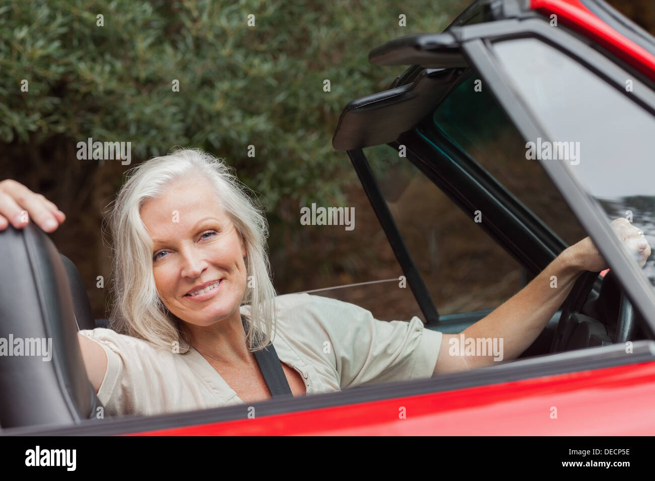 Lächelnde Reife Frau posiert in roten Cabrio Stockfoto
