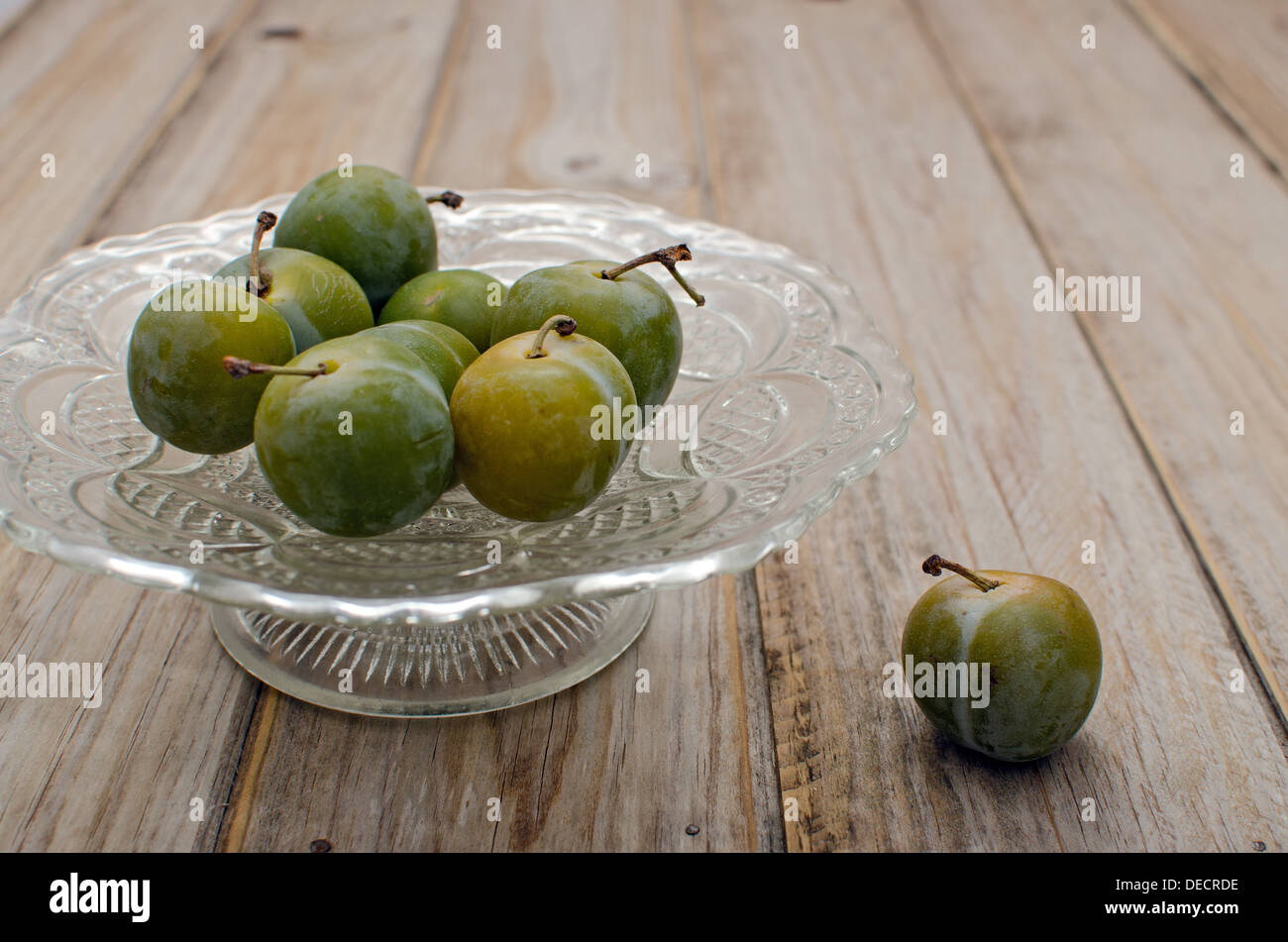 Glasschale mit Pflaumen auf einem Holztisch Stockfoto