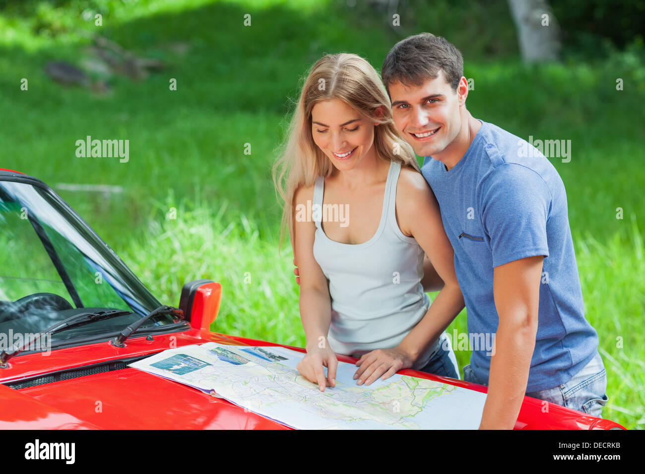 Fröhliches junges Paar Lesung Karte auf ihre Cabriolet Motorhaube Stockfoto