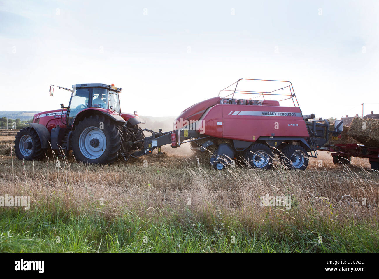 Eine rote Massey Ferguson Traktor und Ballenpresse Pressen Stroh in der offenen Landschaft. Stockfoto