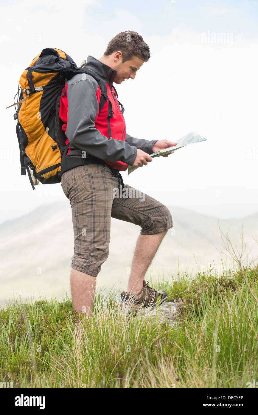 Gut aussehend Wanderer mit Rucksack zu Fuß bergauf Kartenlesen Stockfoto