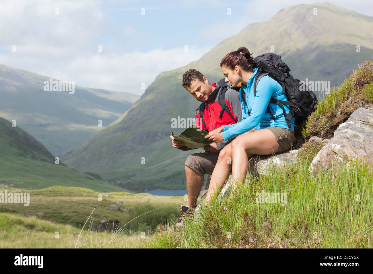 Paar eine Pause nach dem Wandern bergauf und Lesung Karte Stockfoto