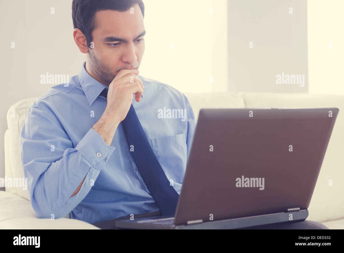 Mann mit einem Laptop auf einem Sofa sitzt betont Stockfoto