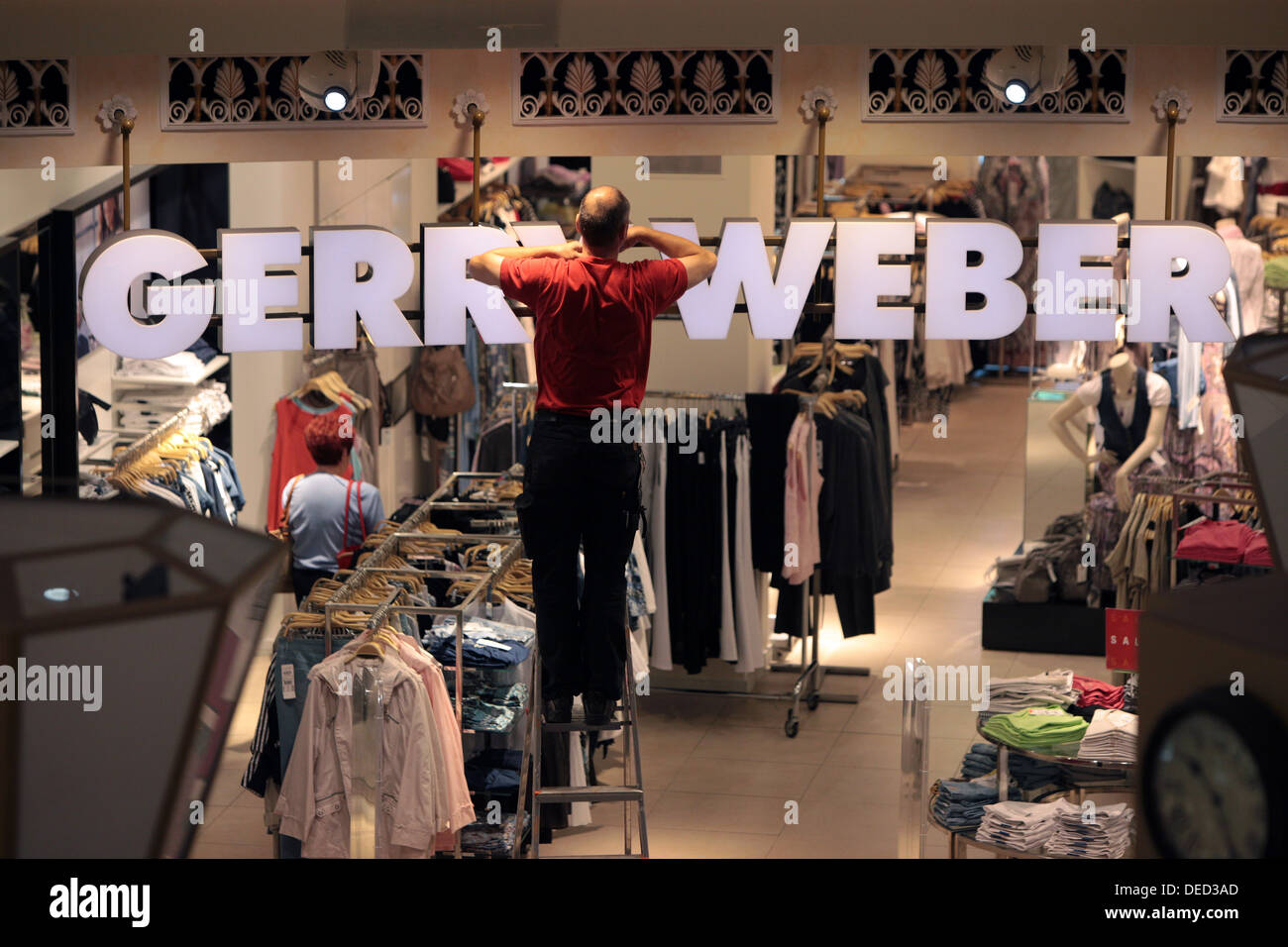 Berlin, Deutschland, steht ein Mann im Gerry Weber Filiale auf einer Leiter Stockfoto