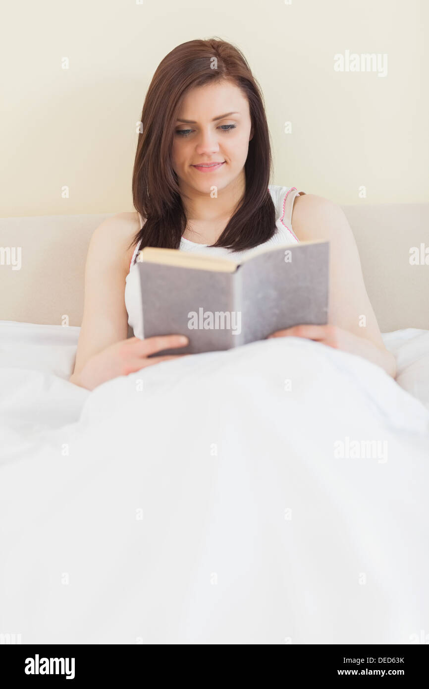 Lächelndes Mädchen ein Buch auf einem Bett liegend Stockfoto