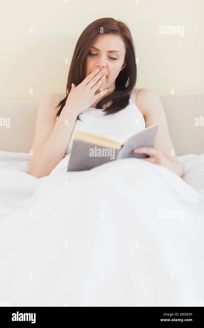Gähnende Mädchen ein Buch auf einem Bett liegend Stockfoto
