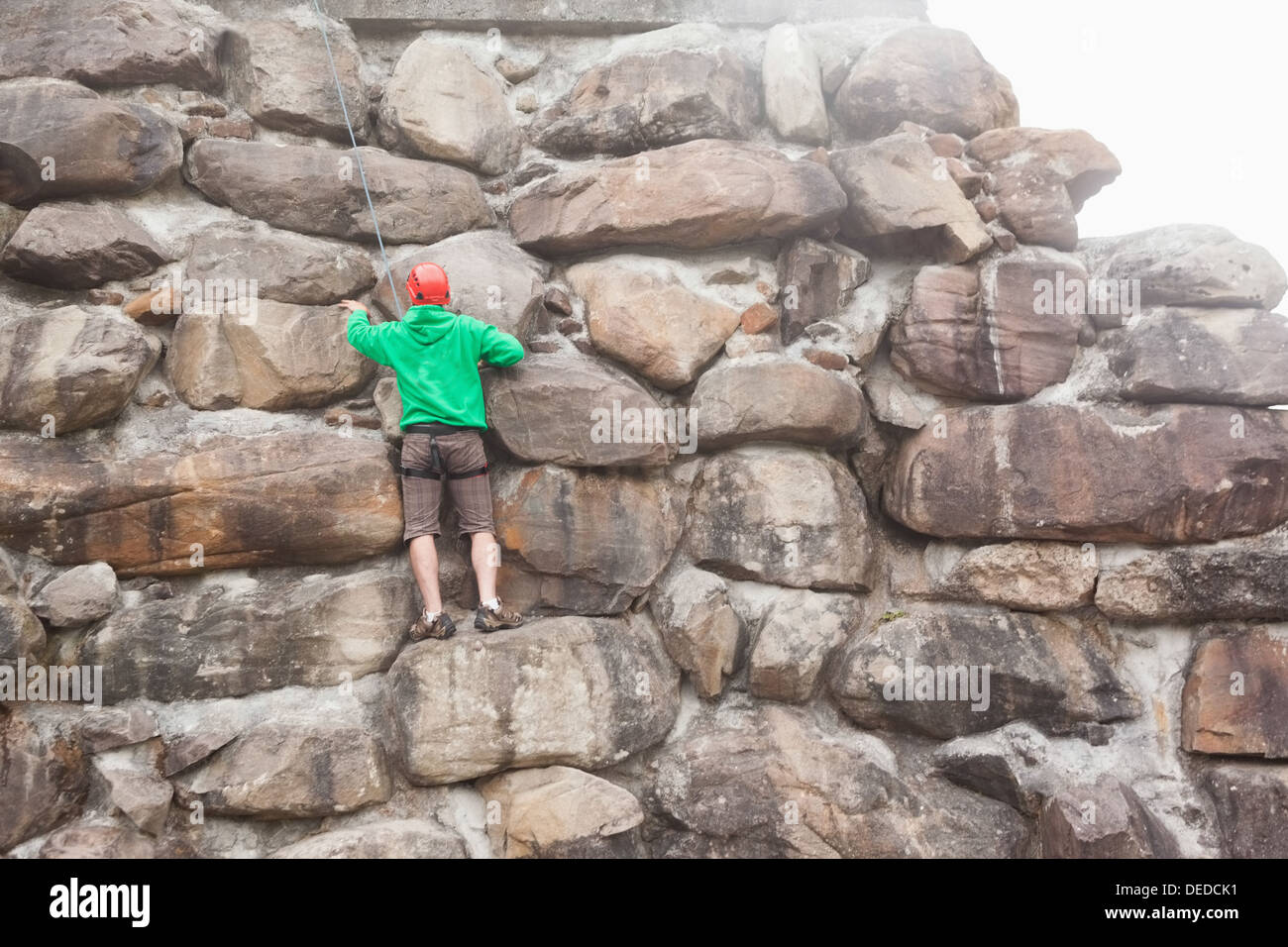 Entschlossenen Mann Skalierung einer großen Felswand Stockfoto