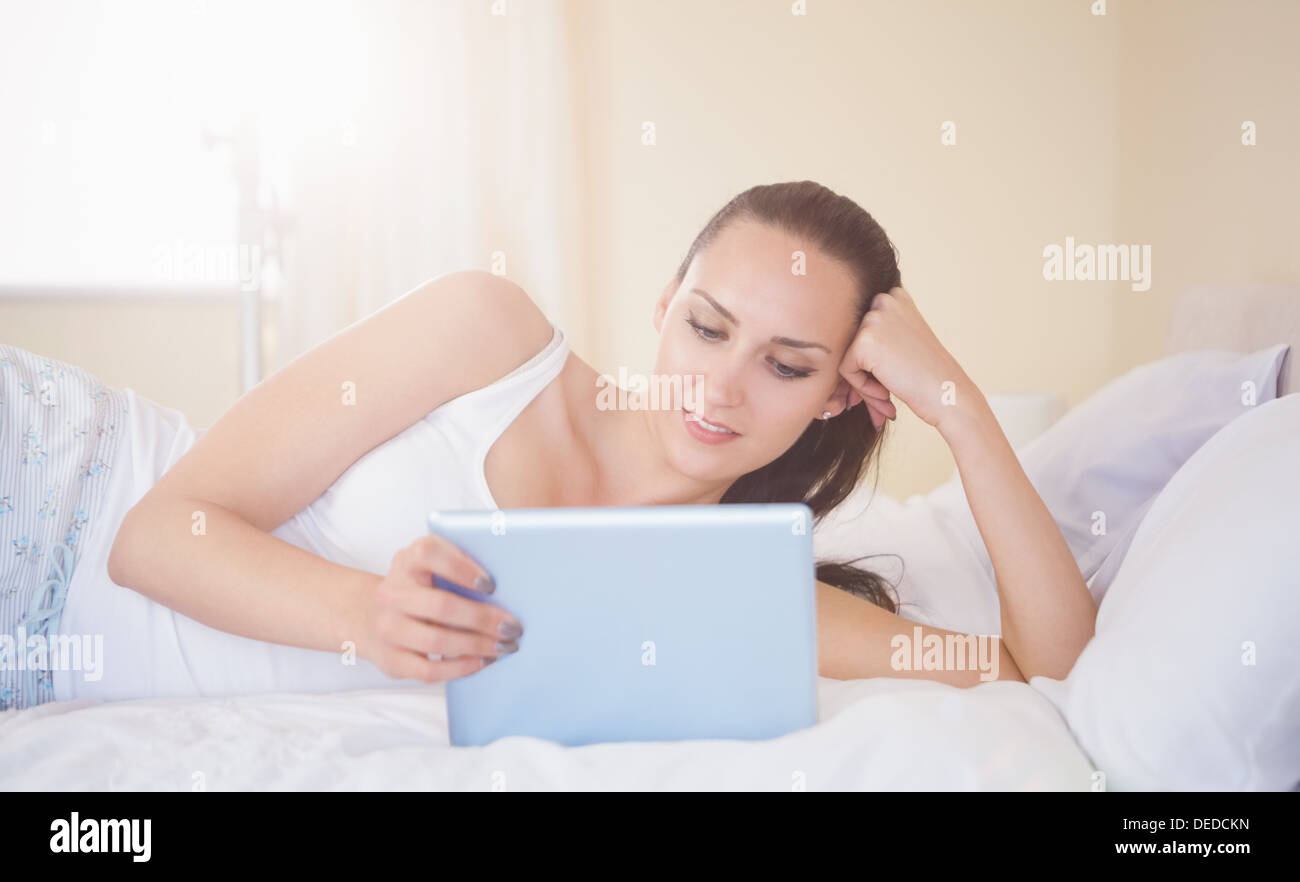 Inhalt Brünette auf Bett mit ihrem Tablet-pc Stockfoto