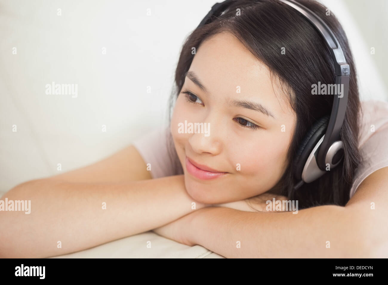 Entspannende asiatische Mädchen auf dem Sofa liegen und Musik hören Stockfoto