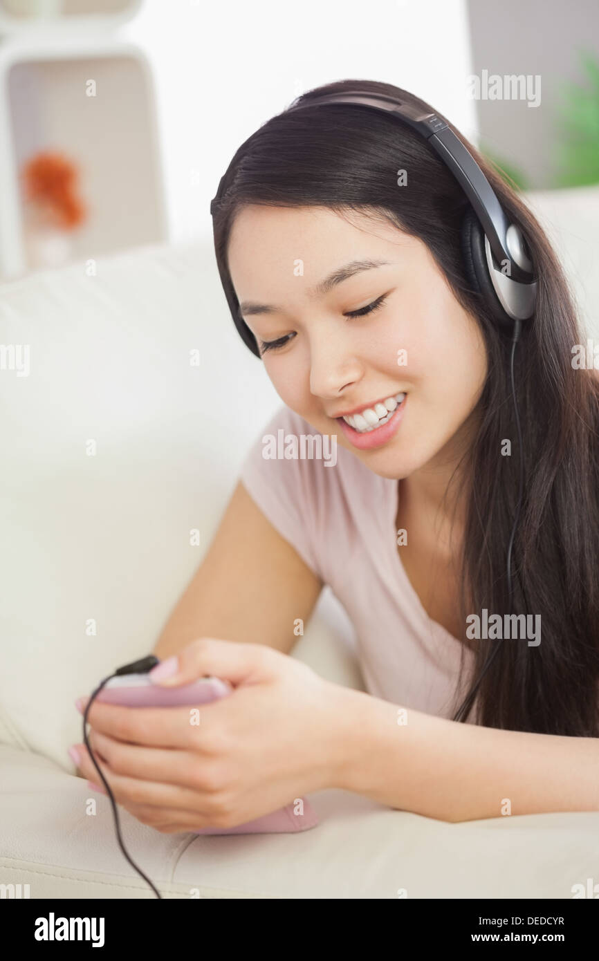 Entspannende asiatische Mädchen auf dem Sofa liegend und Musikhören mit smartphone Stockfoto