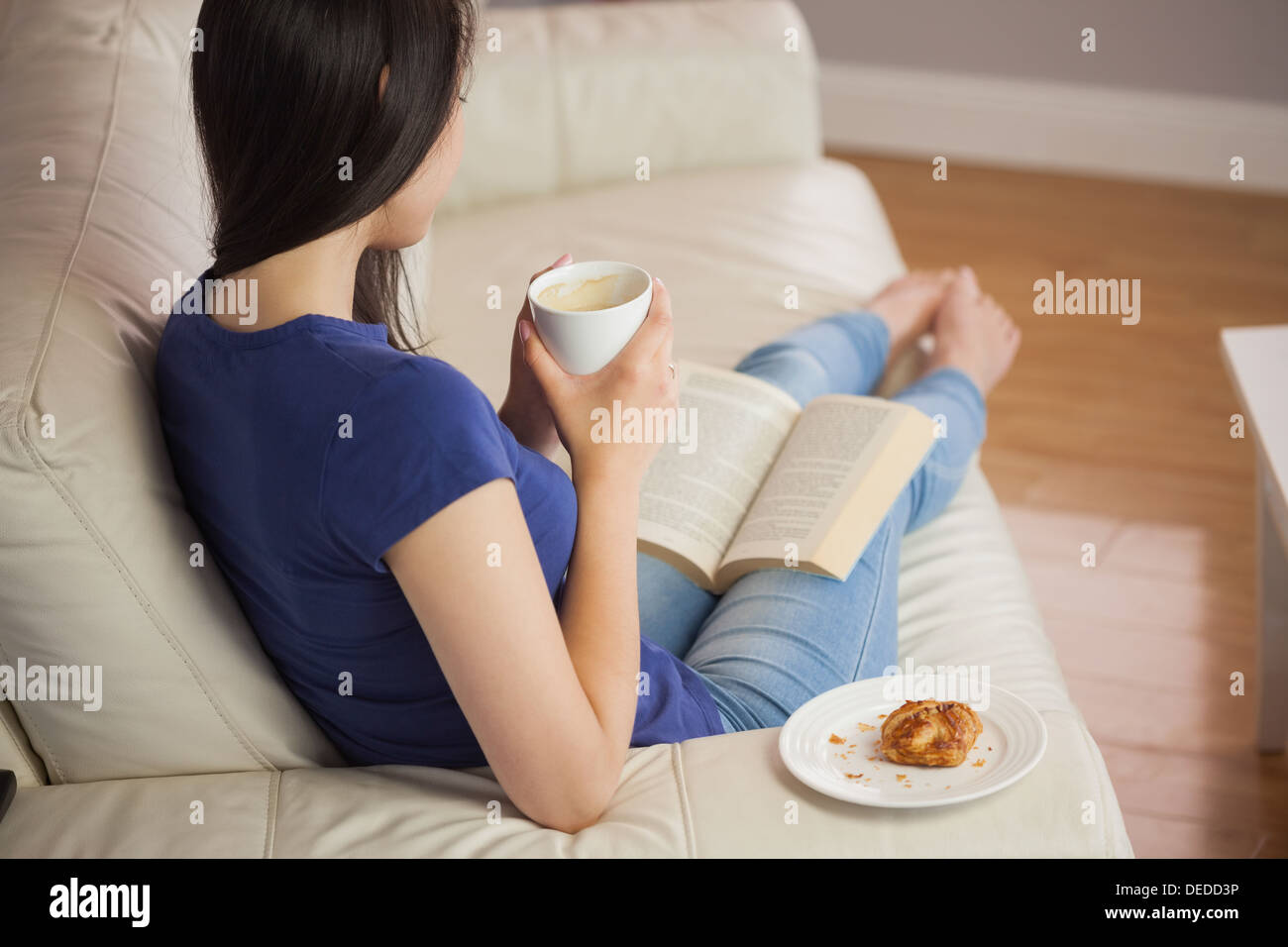 Junge Frau hält ihren Kaffee und Buch Stockfoto