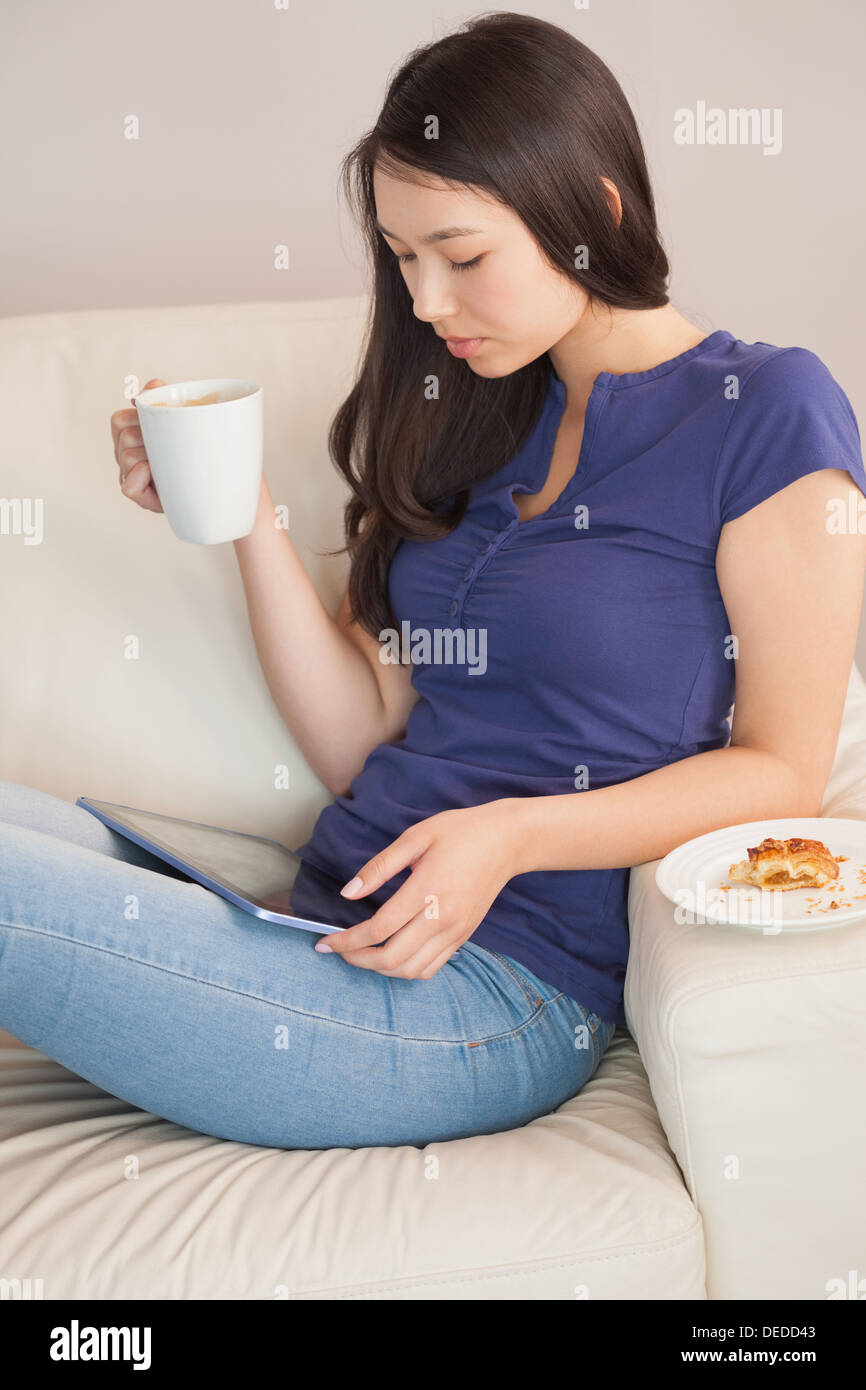 Junge Frau mit ihrem TabletPC und hält Becher Kaffee Stockfoto