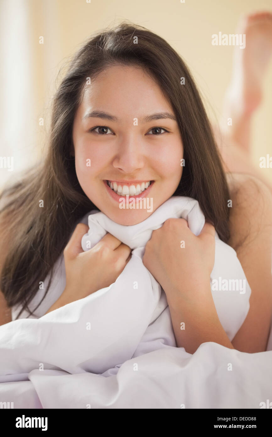 Süße junge Asiatin hält ihre Bettdecke lächelnd Stockfoto