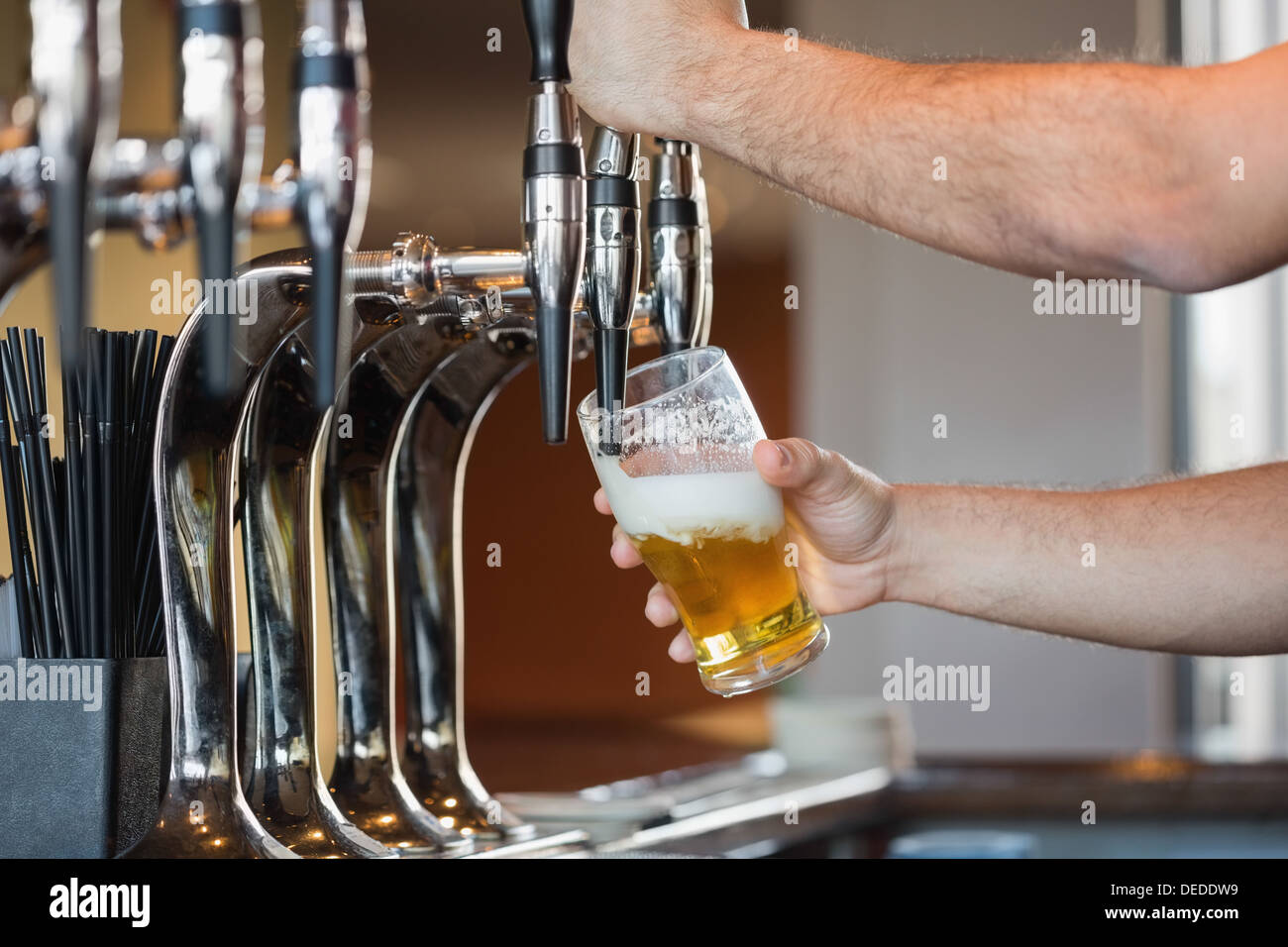 Barmans Arme ziehen einen Pint Bier Stockfoto