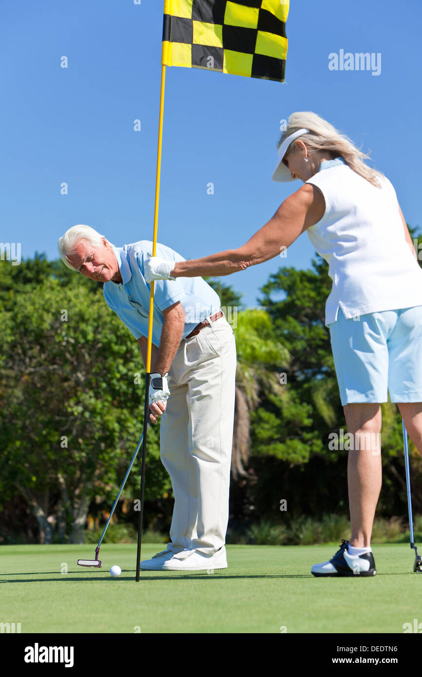 Glücklich senior Mann und Frau Paar zusammen spielen Golf auf einem grünen Zusammenstellung Stockfoto