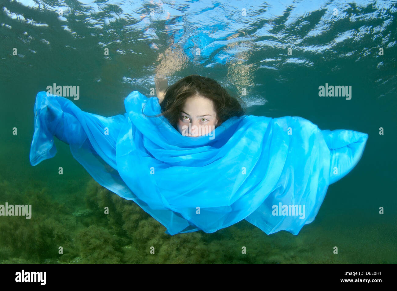 Eine junge Frau mit langen Haaren in blauem Kleid Tauchgänge Unterwasser im Schwarzen Meer Stockfoto