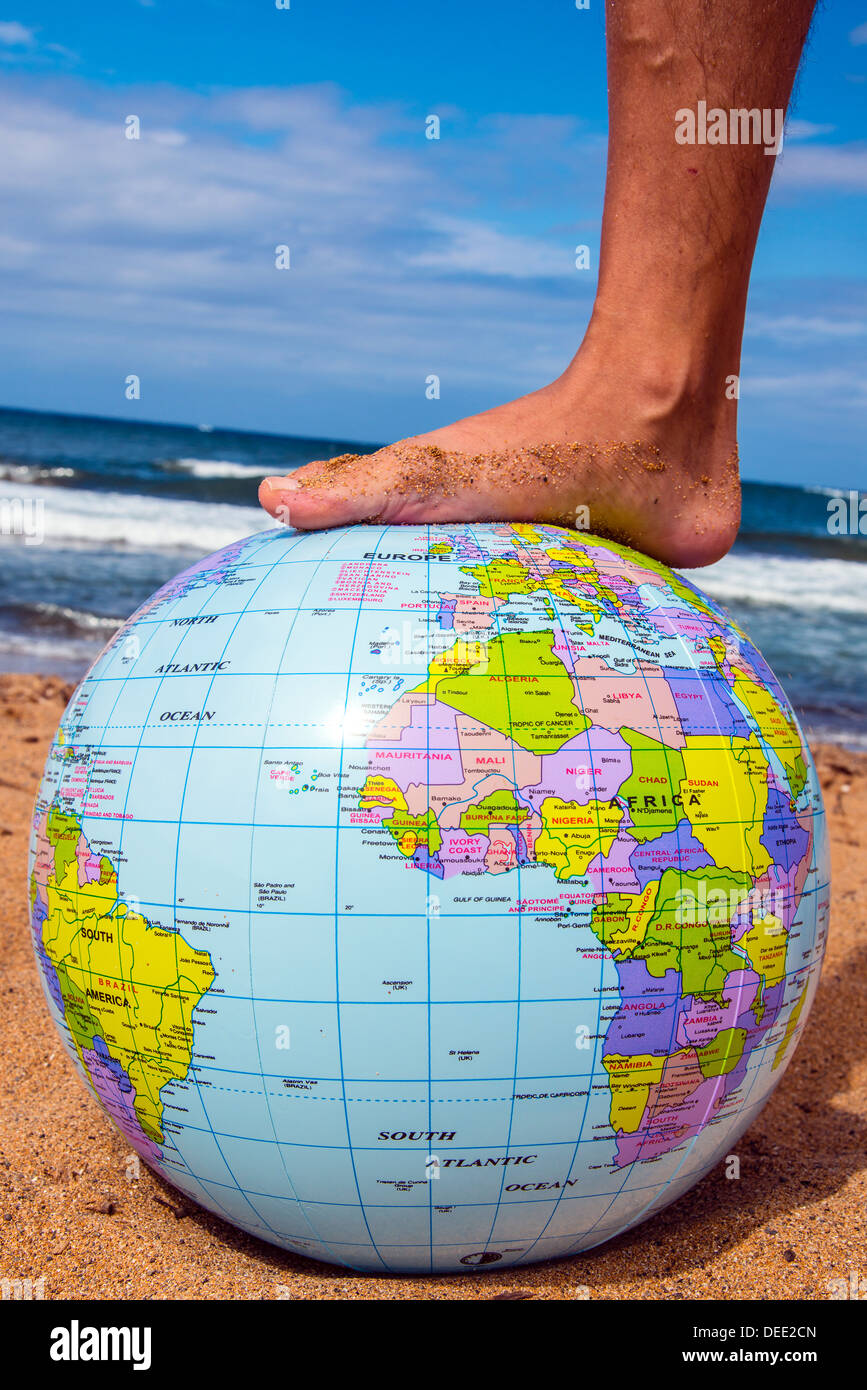 Männlichen Fuß auf eine aufblasbare Erde Strandball mit Meer hinter Stockfoto