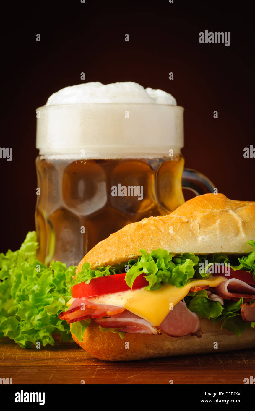 Stillleben mit Deli-Sub-Baguette-Sandwich und Bier Stockfoto