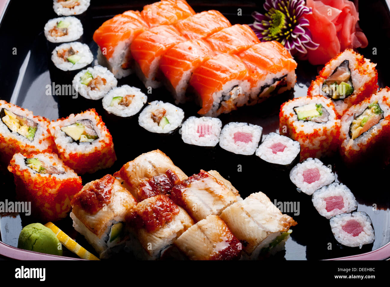 Verschiedene Sushi-Rollen auf einer schwarzen Platte. Stockfoto