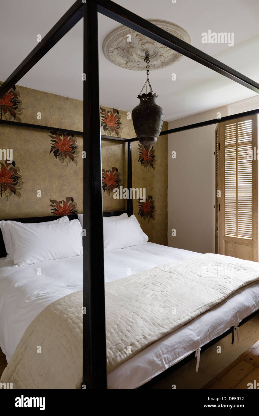 Kolonialstil vier Himmelbett im Zimmer mit marokkanische Laterne und floral gemusterten Tapete Stockfoto