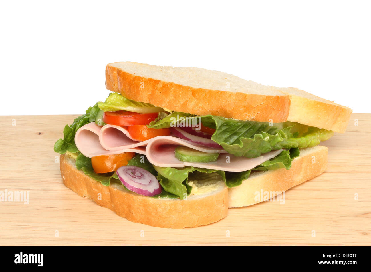 Schinken und Salat-Sandwich auf einem Holzbrett vor einem weißen Hintergrund Stockfoto