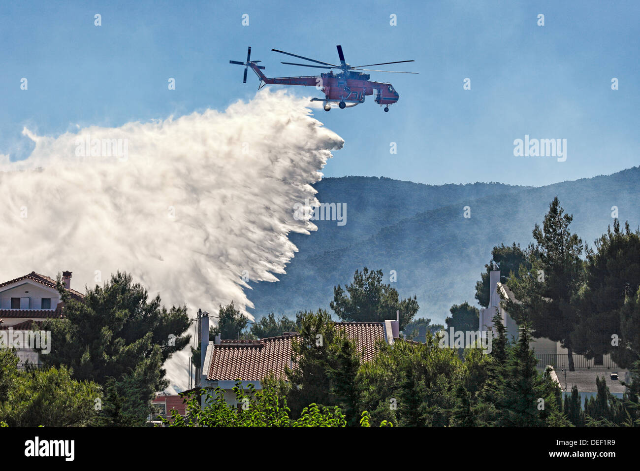 Eine Hubschrauber zur Brandbekämpfung erlischt das Feuer über Häuser Stockfoto